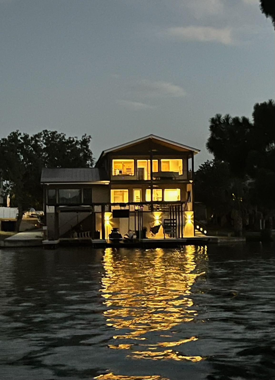 ThermaSteel residence on the water at dusk with warm interior lights reflecting across the surface